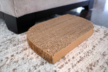 Cat scratching pad next to furniture