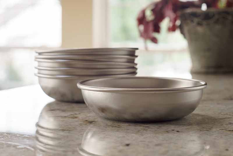 6 stainless steel cat bowls on a counter